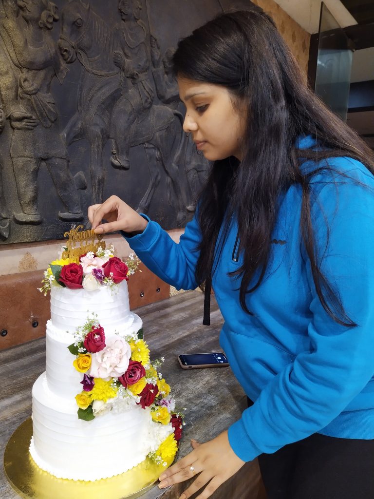 a girl decorating a wedding cake with flowers